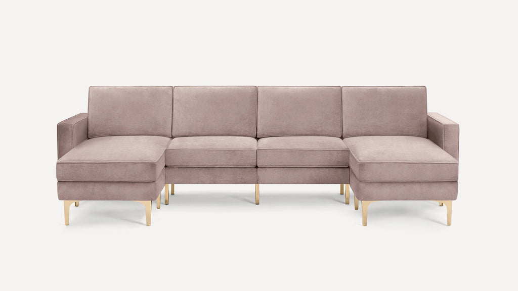 Modern U-shaped sectional sofa in muted pink velvet with gold metal legs, featuring clean lines and plush cushions.