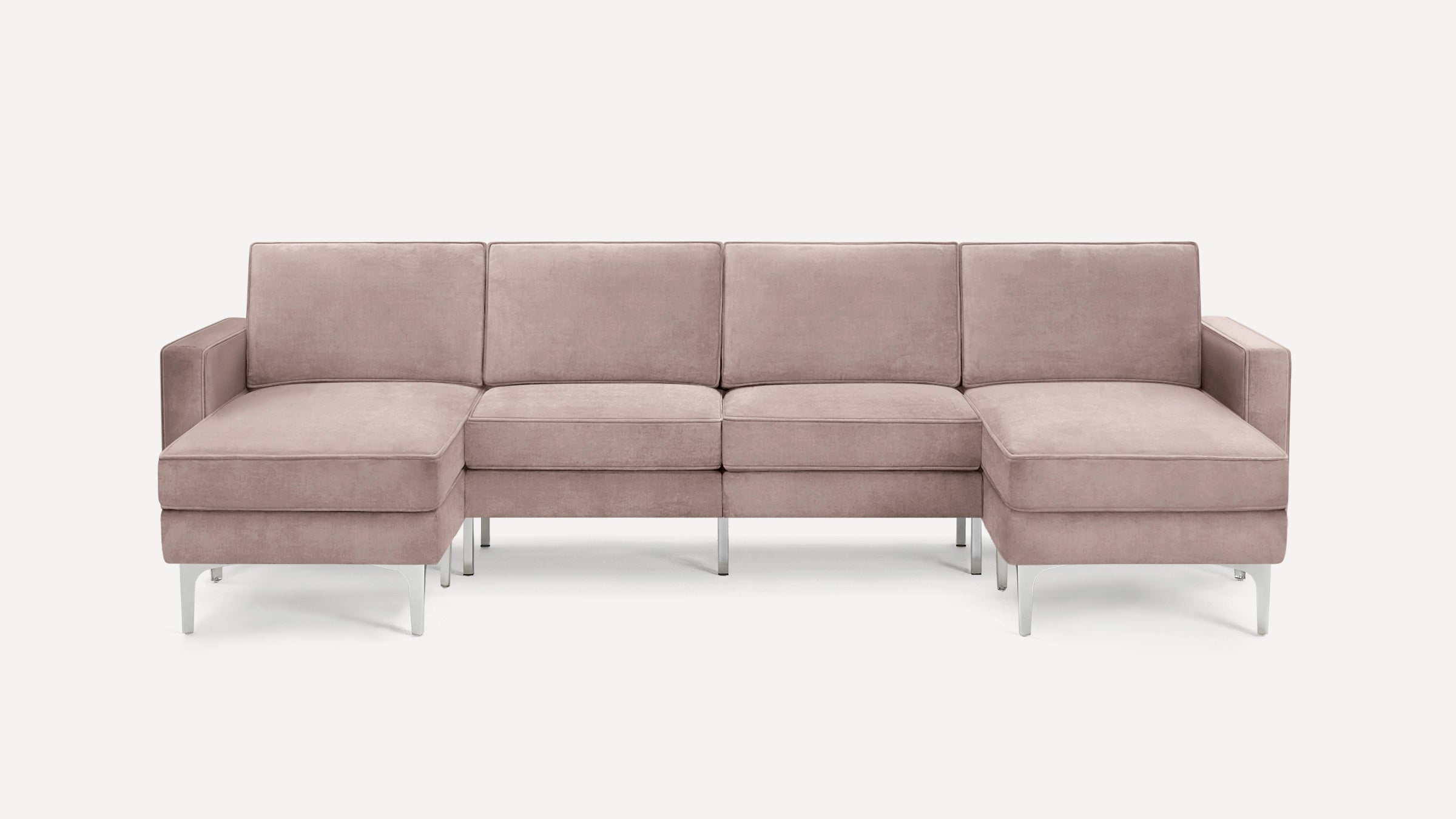 Modern U-shaped sectional sofa in soft blush pink fabric with cushioned seats and metal legs on white background.