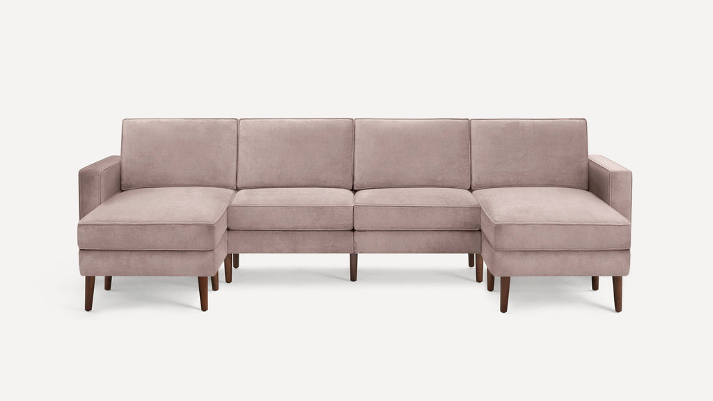 Modern sectional sofa with light mauve upholstery, wooden legs, and symmetrical chaise lounges on both ends.