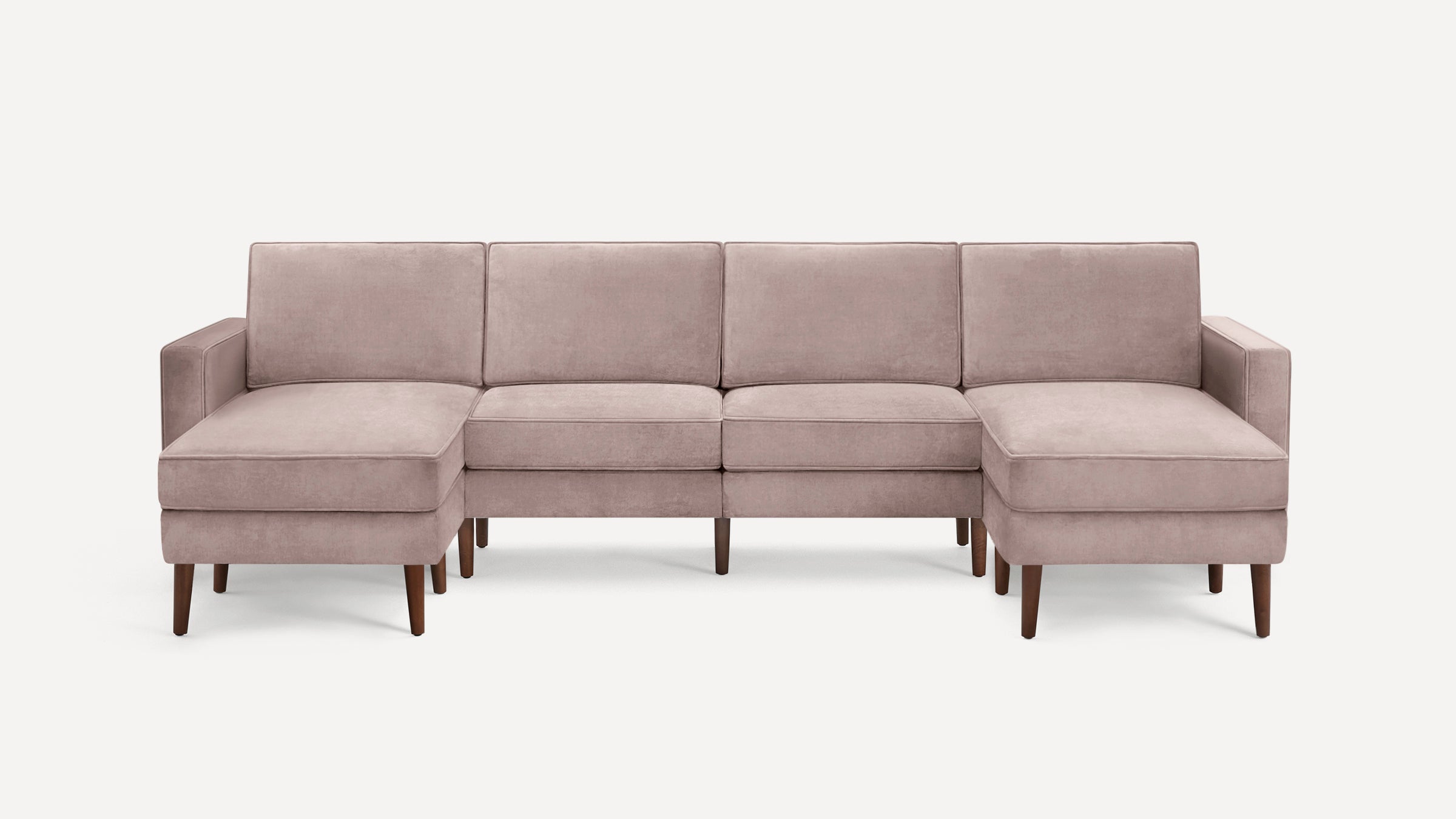 Modern sectional sofa with light mauve upholstery, wooden legs, and symmetrical chaise lounges on both ends.