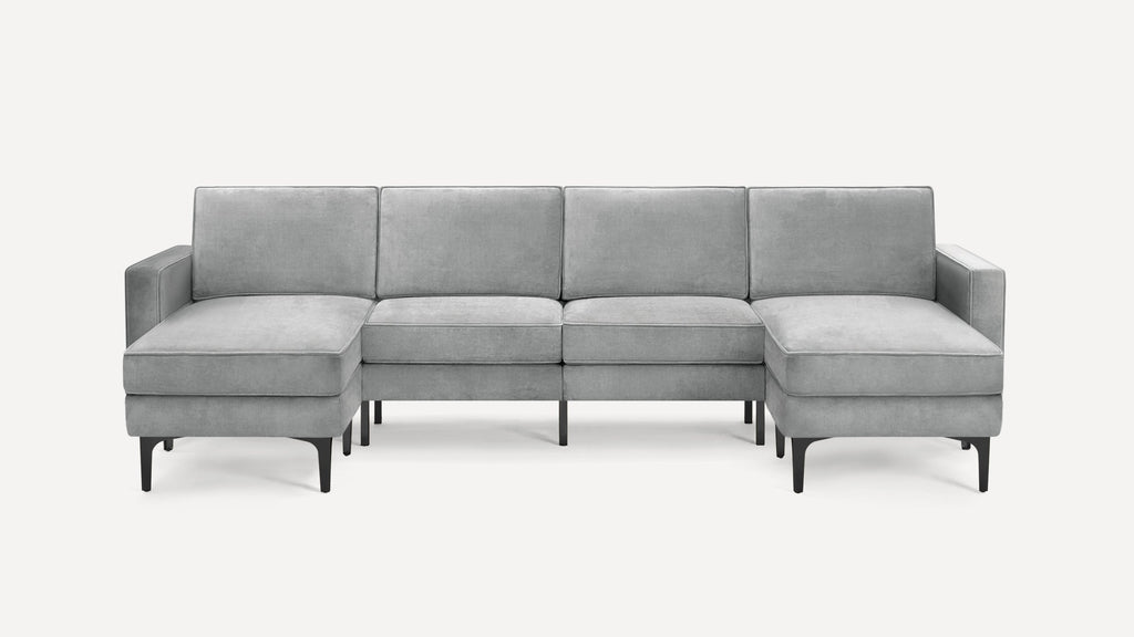 Light gray modern sectional sofa with velvet upholstery, high back cushions, armrests on both ends, and black slender legs.
