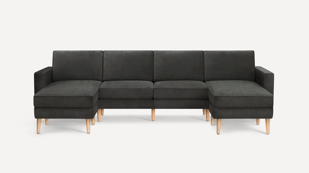 Modern dark gray fabric sectional sofa with wooden legs and chaise lounge on both ends, set against a plain white background.