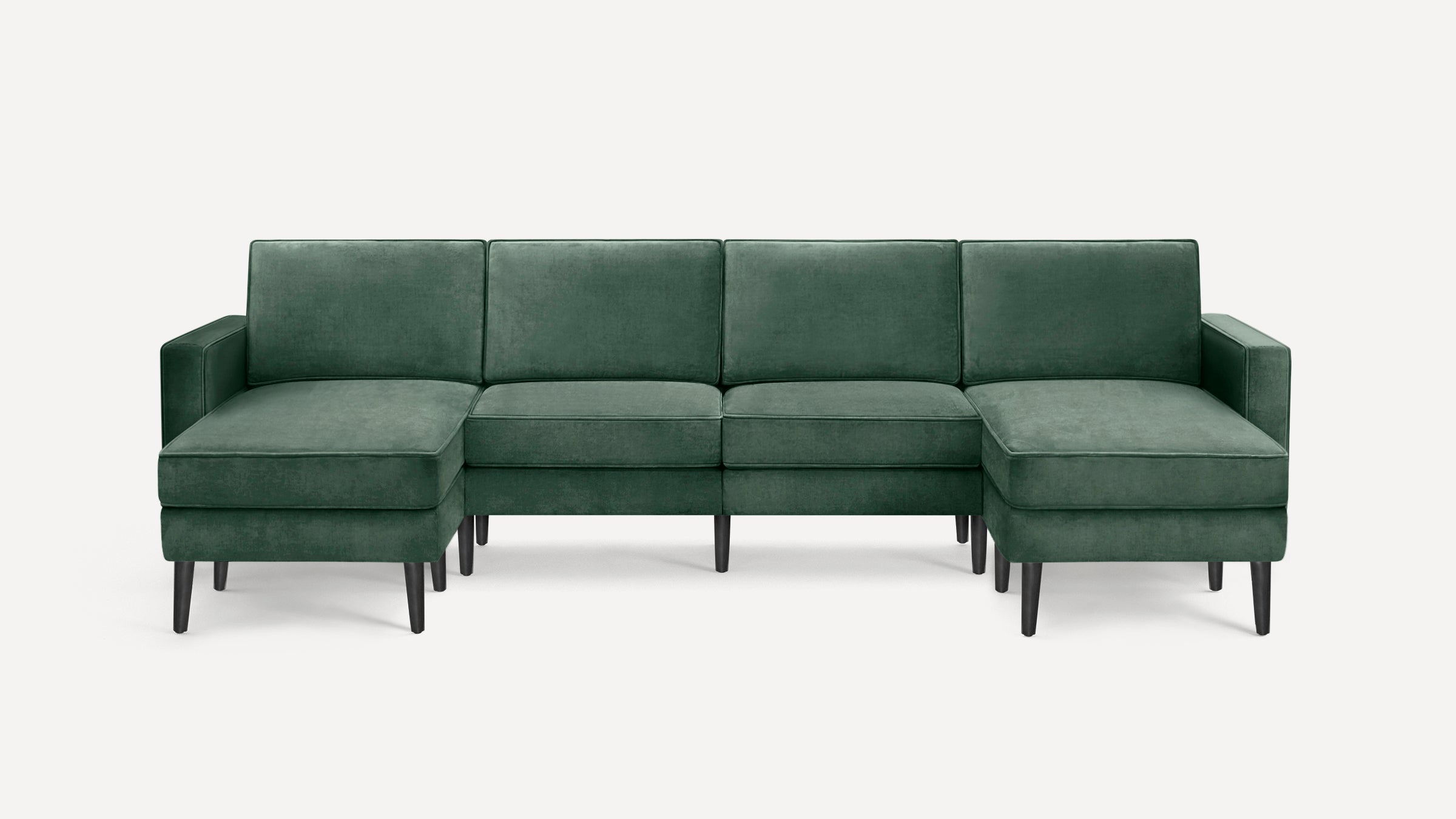 Green velvet L-shaped sectional sofa with armrests and wooden tapered legs, modern and spacious design.