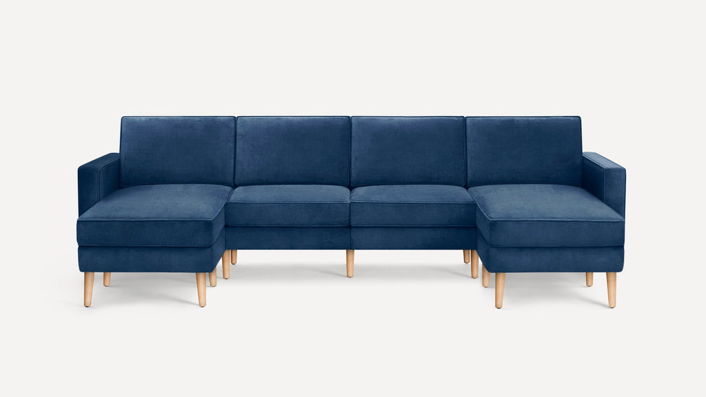 Modern navy blue sectional sofa with plush cushions, wooden legs, and a symmetrical L-shaped design on both ends.