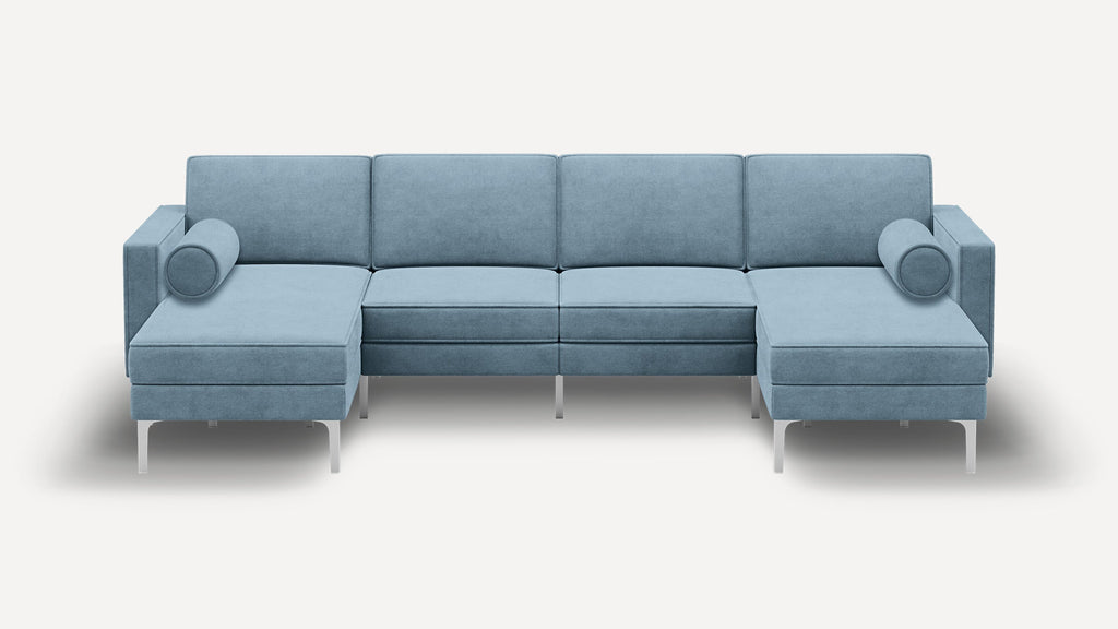 Modern light blue velvet sectional sofa with metal legs, two chaise lounges, and two cylindrical bolster pillows.
