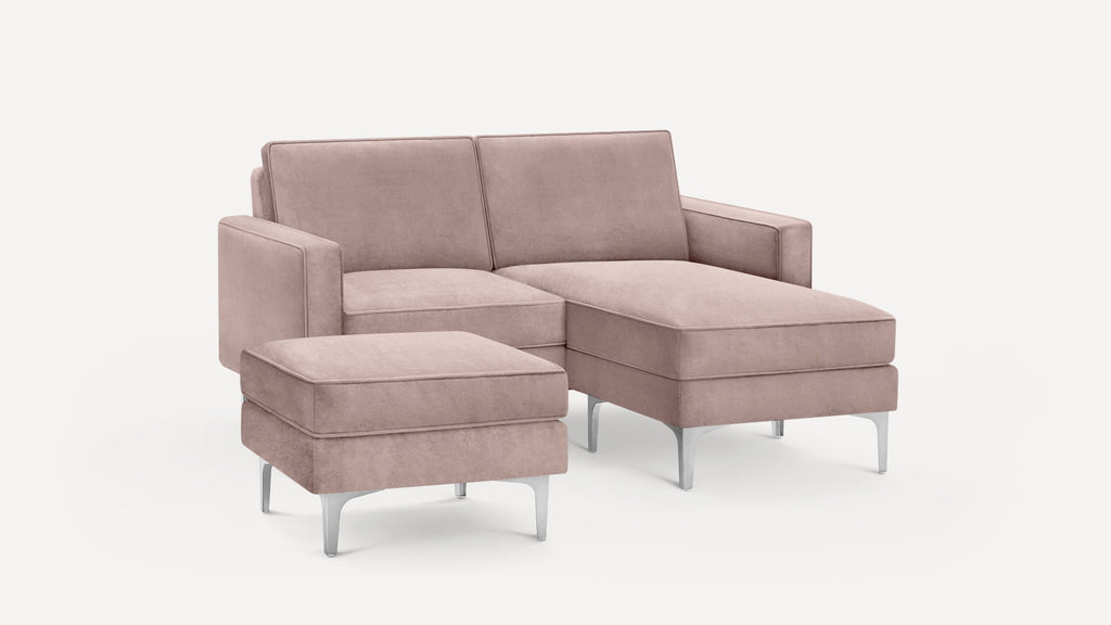 Modern blush pink sectional sofa with plush cushions and metal legs, accompanied by a matching ottoman.