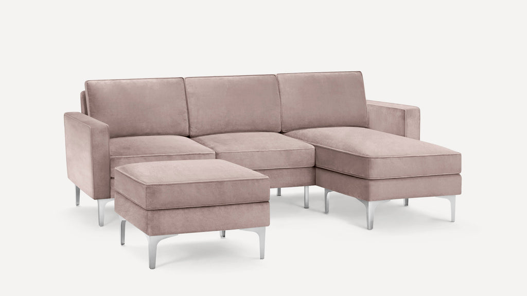 Modern light pink velvet sectional sofa with matching ottoman, featuring sleek silver legs and clean lines.