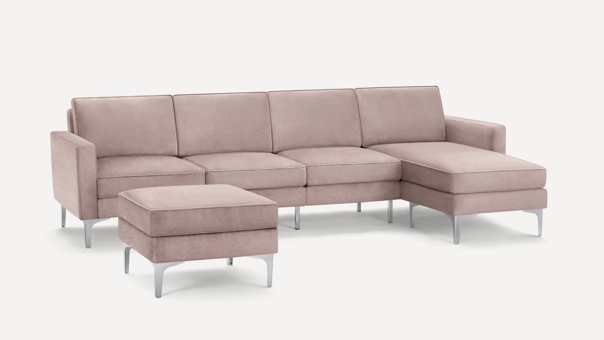 Blush pink sectional sofa with clean lines, metal legs, and a matching ottoman, set against a plain white background.