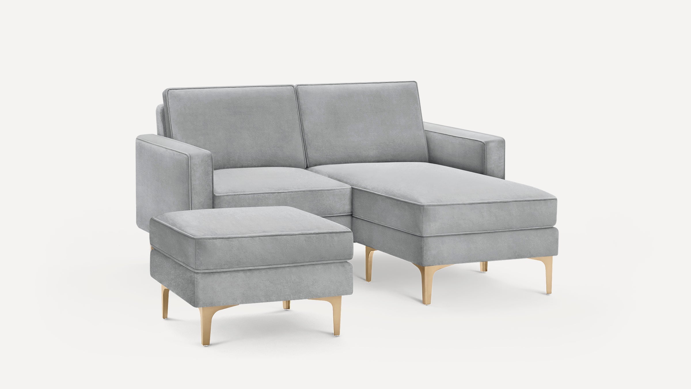 Modern light gray velvet sectional sofa with chaise lounge and matching ottoman, featuring gold metal legs.