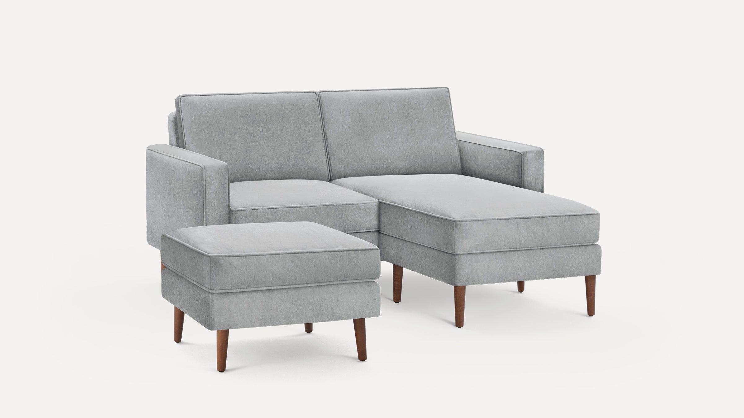 Light gray modern sectional sofa with matching ottoman, wooden tapered legs, and clean boxy design.