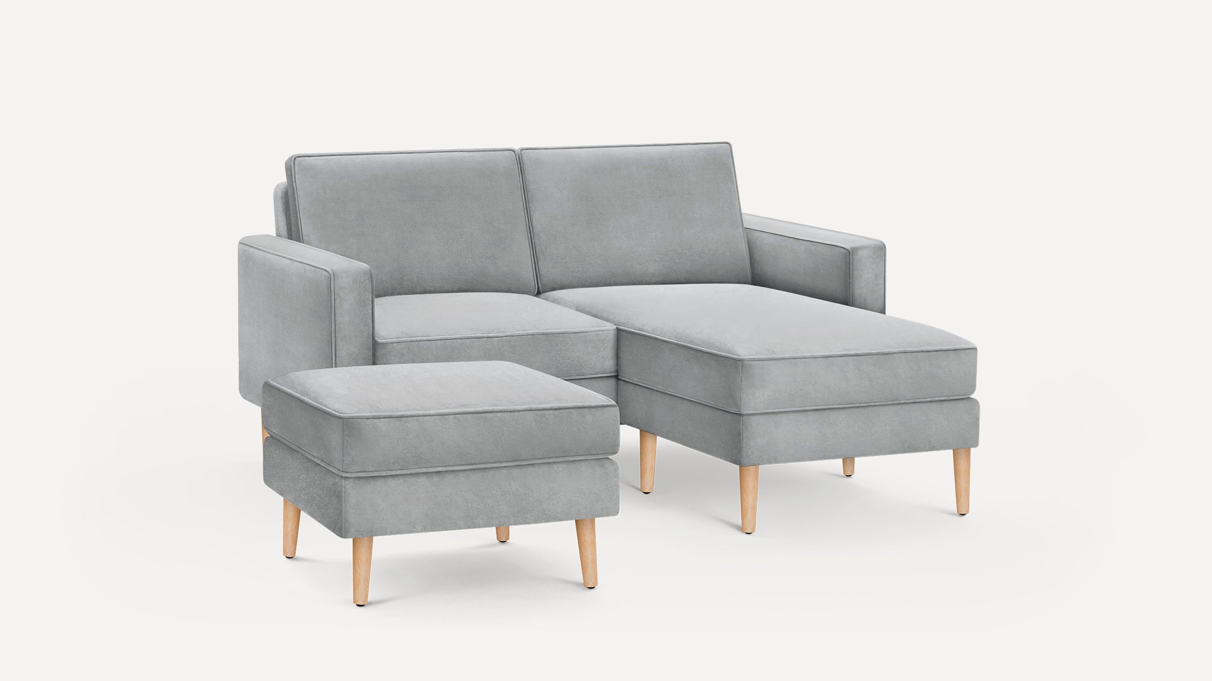 Modern light gray fabric chaise sofa with matching ottoman, wooden tapered legs, and clean-lined armrests.
