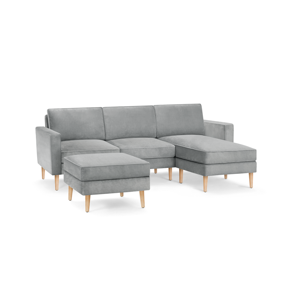 modern l - shaped sectional sofa with light gray fabric upholstery, tapered wooden legs, and matching ottoman, featuring a clean, modern