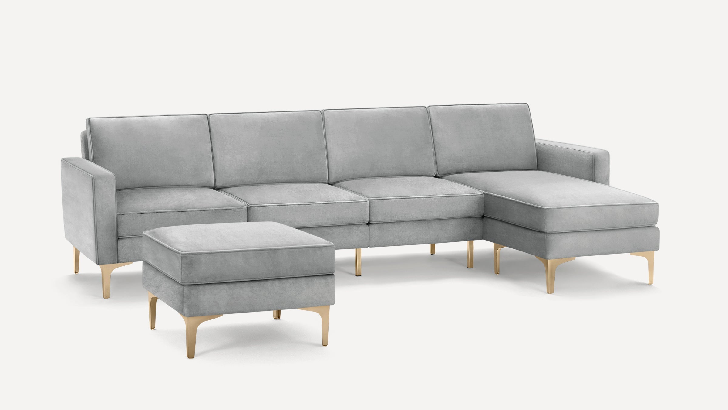 Light gray velvet sectional sofa with matching ottoman, both featuring sleek gold metal legs, modern and elegant design.