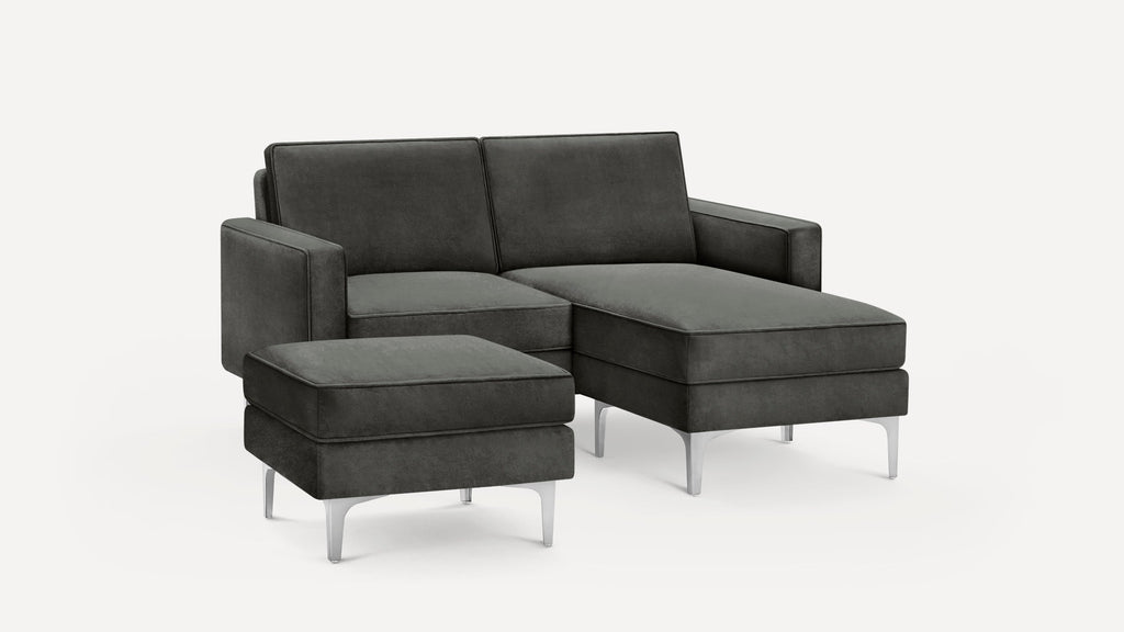 Dark gray upholstered sectional sofa with matching ottoman, featuring clean lines and metal legs, on a white background.
