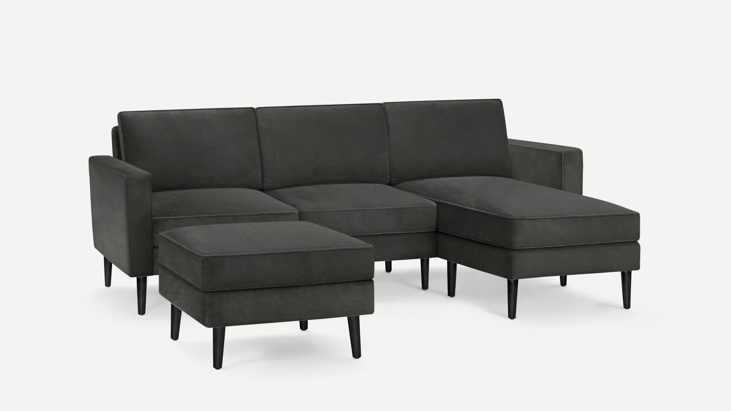 Dark gray modern sectional sofa with clean lines, three seat cushions, chaise lounge on the right, and matching ottoman.