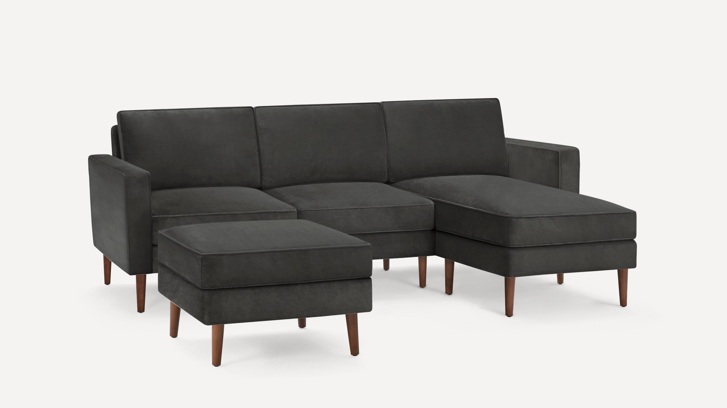 Dark gray modern sectional sofa with chaise lounge and matching ottoman, supported by wooden legs.