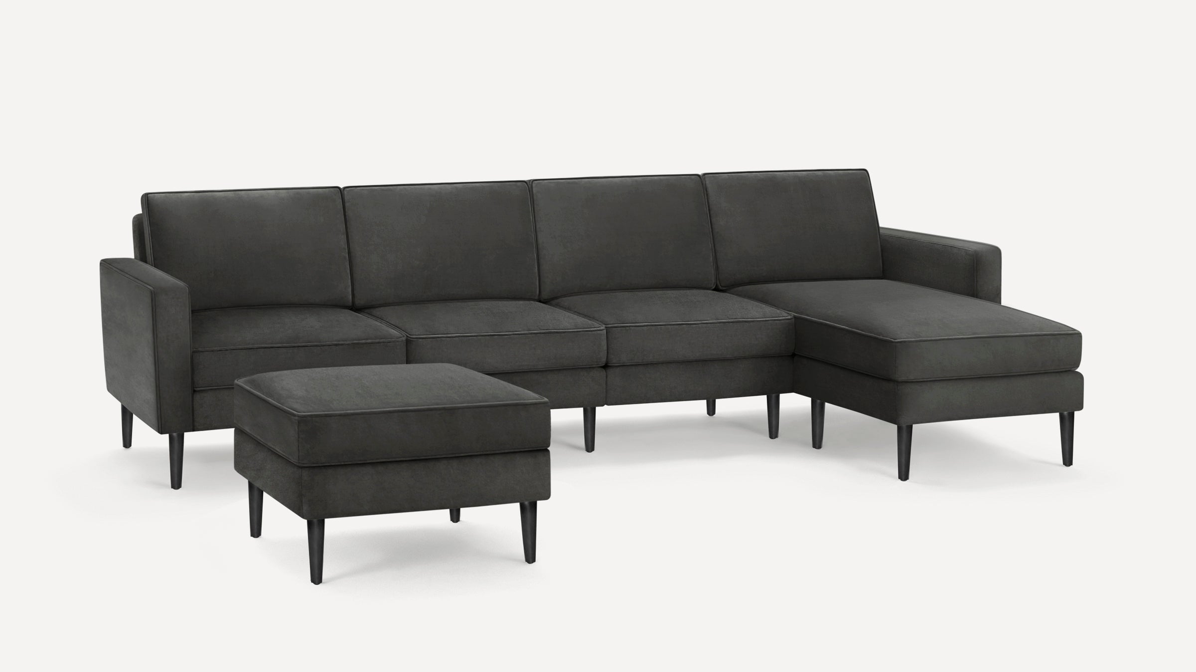 Modern dark gray sectional sofa with chaise lounge and matching ottoman, featuring clean lines and tapered black legs.