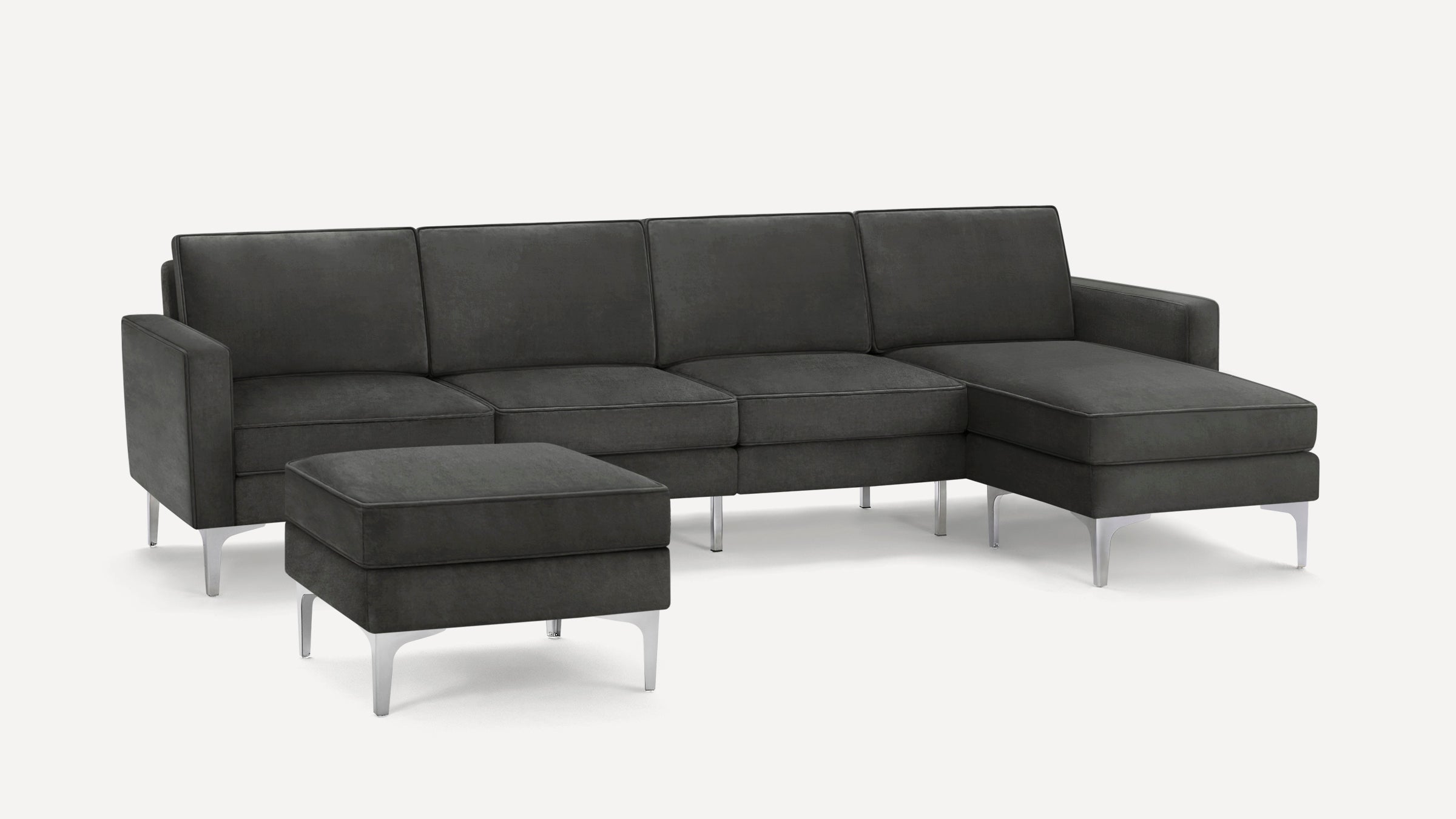 Dark gray modern sectional sofa with chaise lounge and matching ottoman, featuring sleek metal legs.