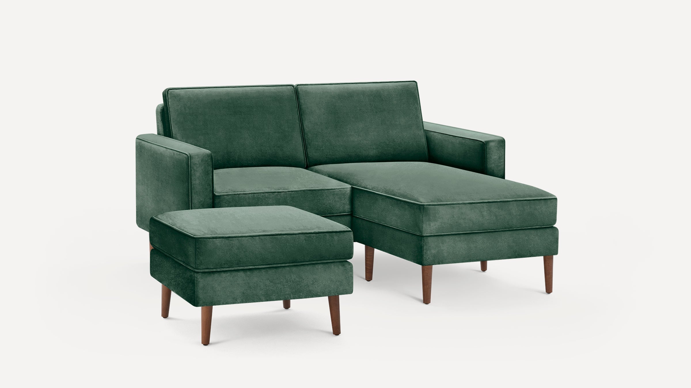 Modern green velvet sectional sofa with matching ottoman, wooden tapered legs, clean lines, and plush cushions.