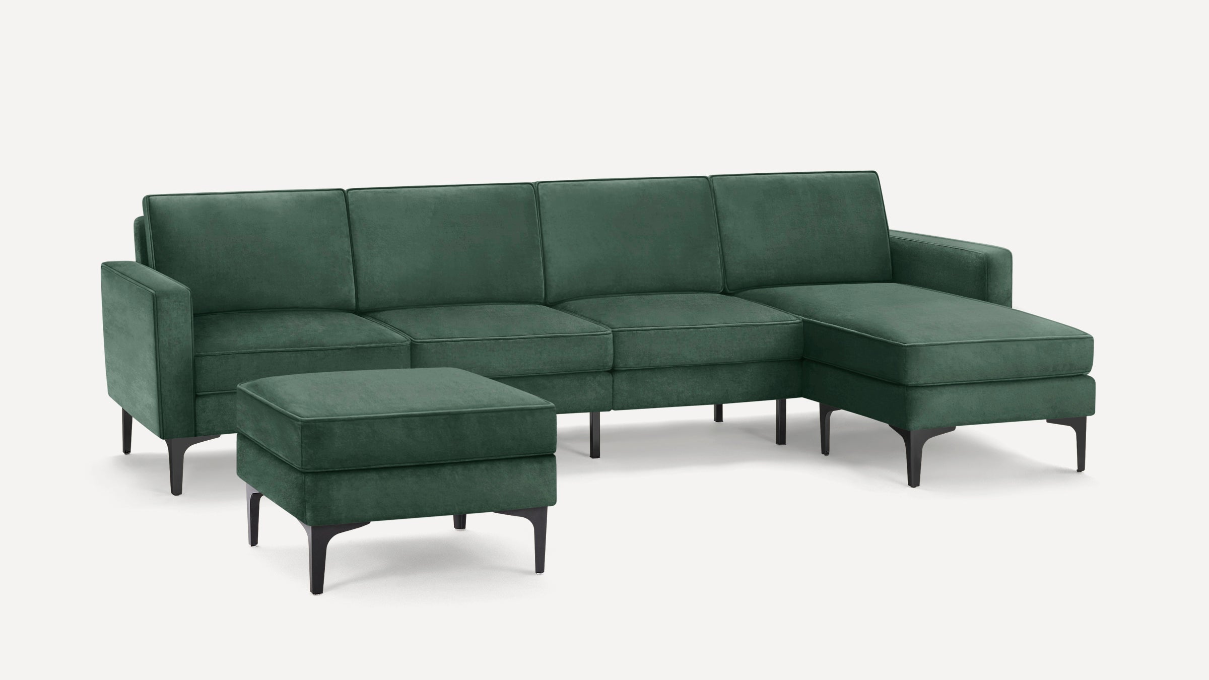 Dark green velvet sectional sofa with chaise lounge and matching ottoman, featuring sleek black legs and modern design.