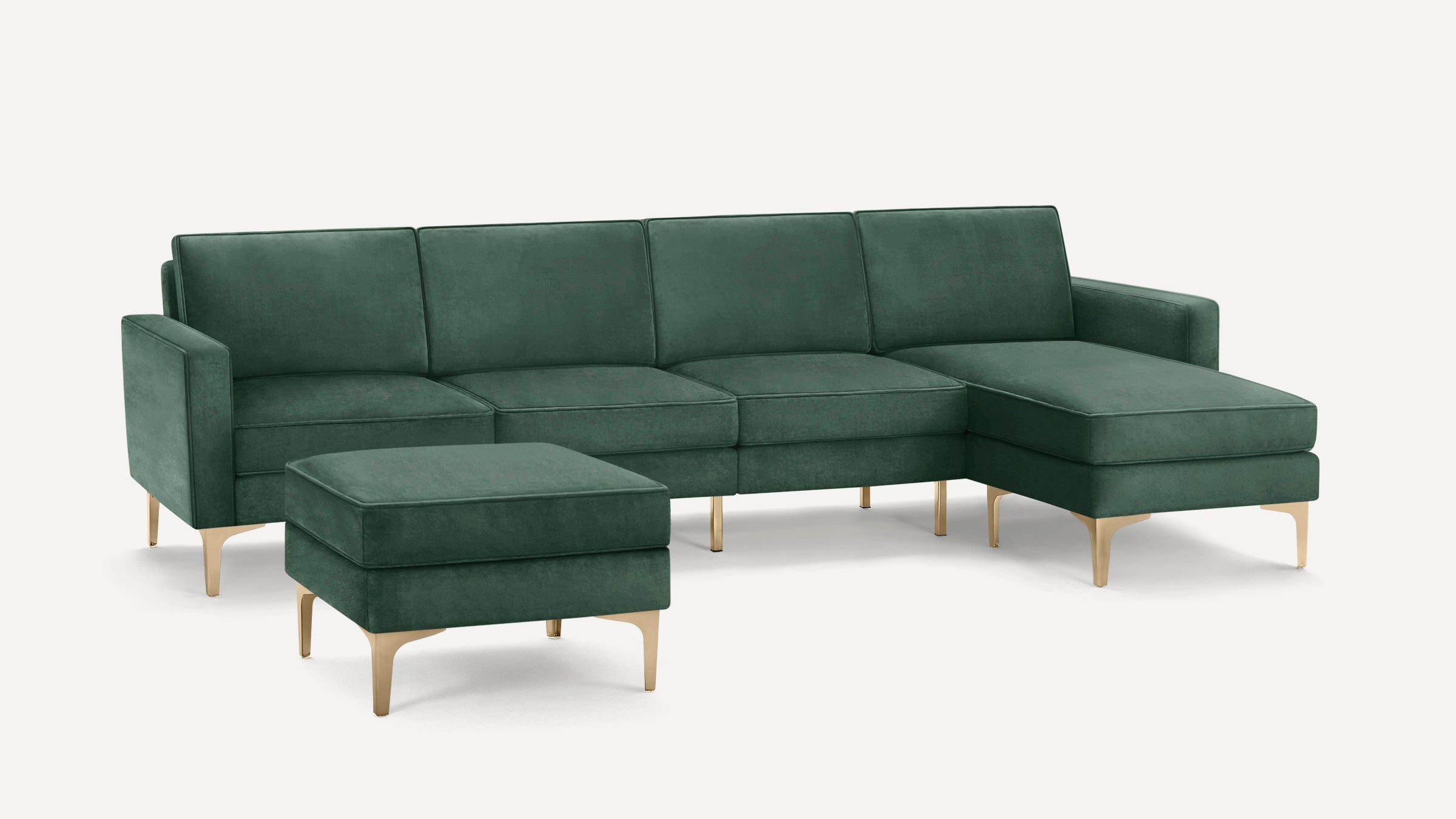 Dark green velvet sectional sofa with tufted cushions and matching ottoman, featuring gold metal legs on a white background.