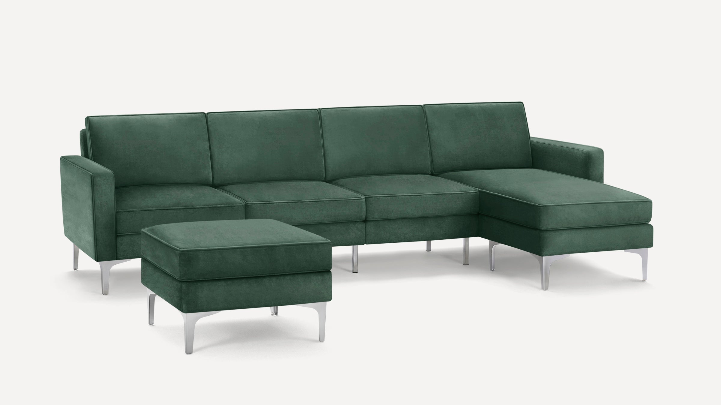 Modern dark green sectional sofa with four seats, chaise lounge on the right, matching ottoman, and sleek silver legs.