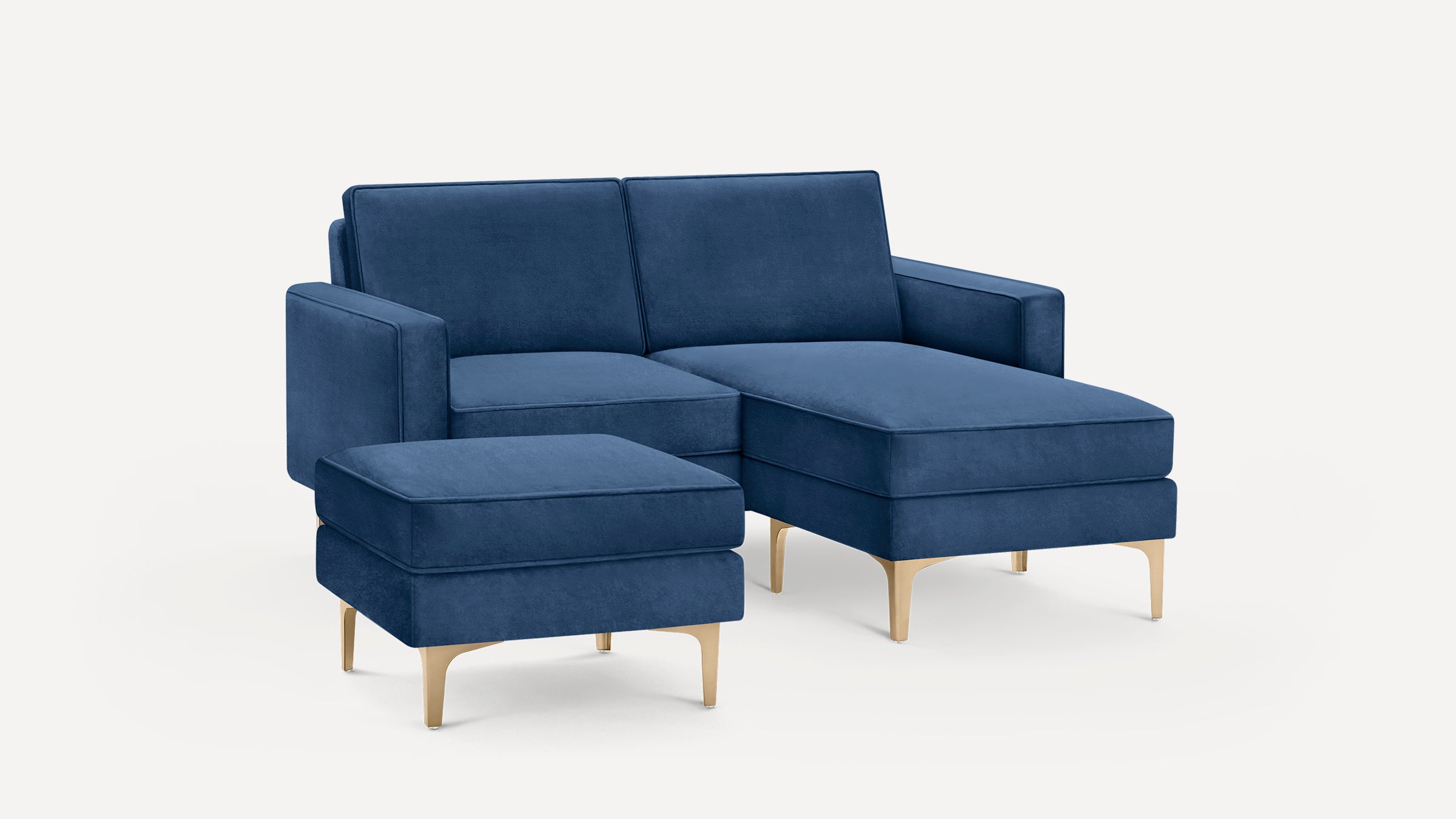 Blue velvet sectional sofa with matching ottoman, featuring sleek gold metal legs and clean, modern lines.