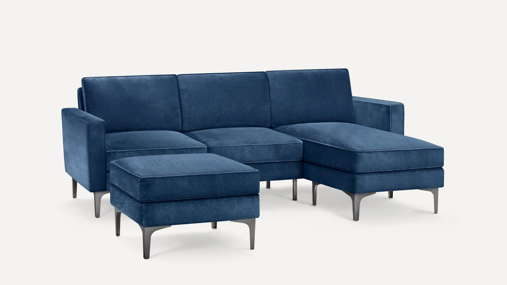 Modern blue velvet sectional sofa with matching ottoman, featuring sleek metal legs and clean, minimalist design.