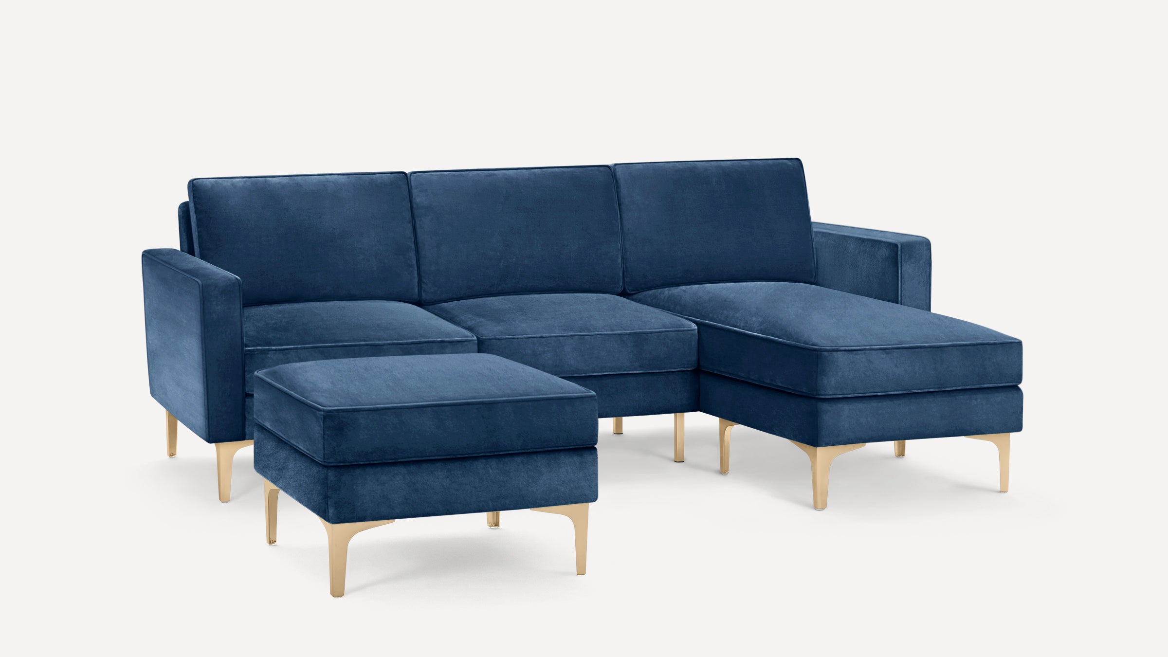 Modern navy blue velvet sectional sofa with matching ottoman, featuring gold metal legs and clean, minimalist design.