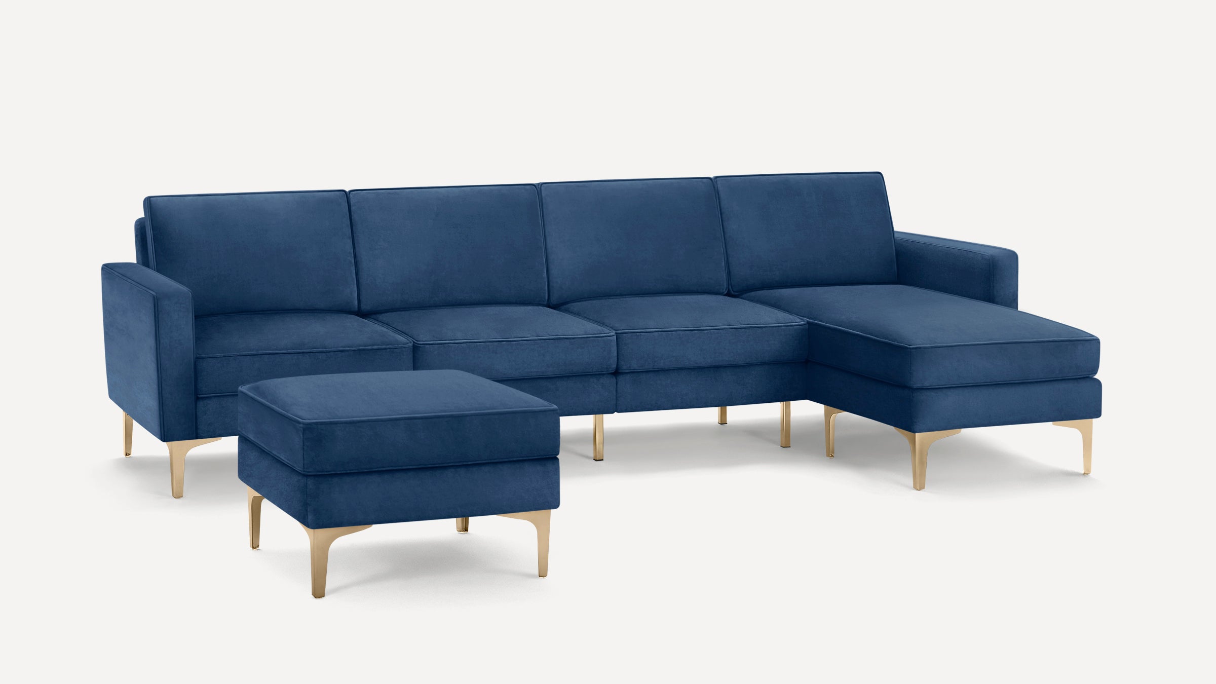 Modern navy blue sectional sofa with chaise lounge and matching ottoman, featuring gold metal legs and sleek velvet upholstery.