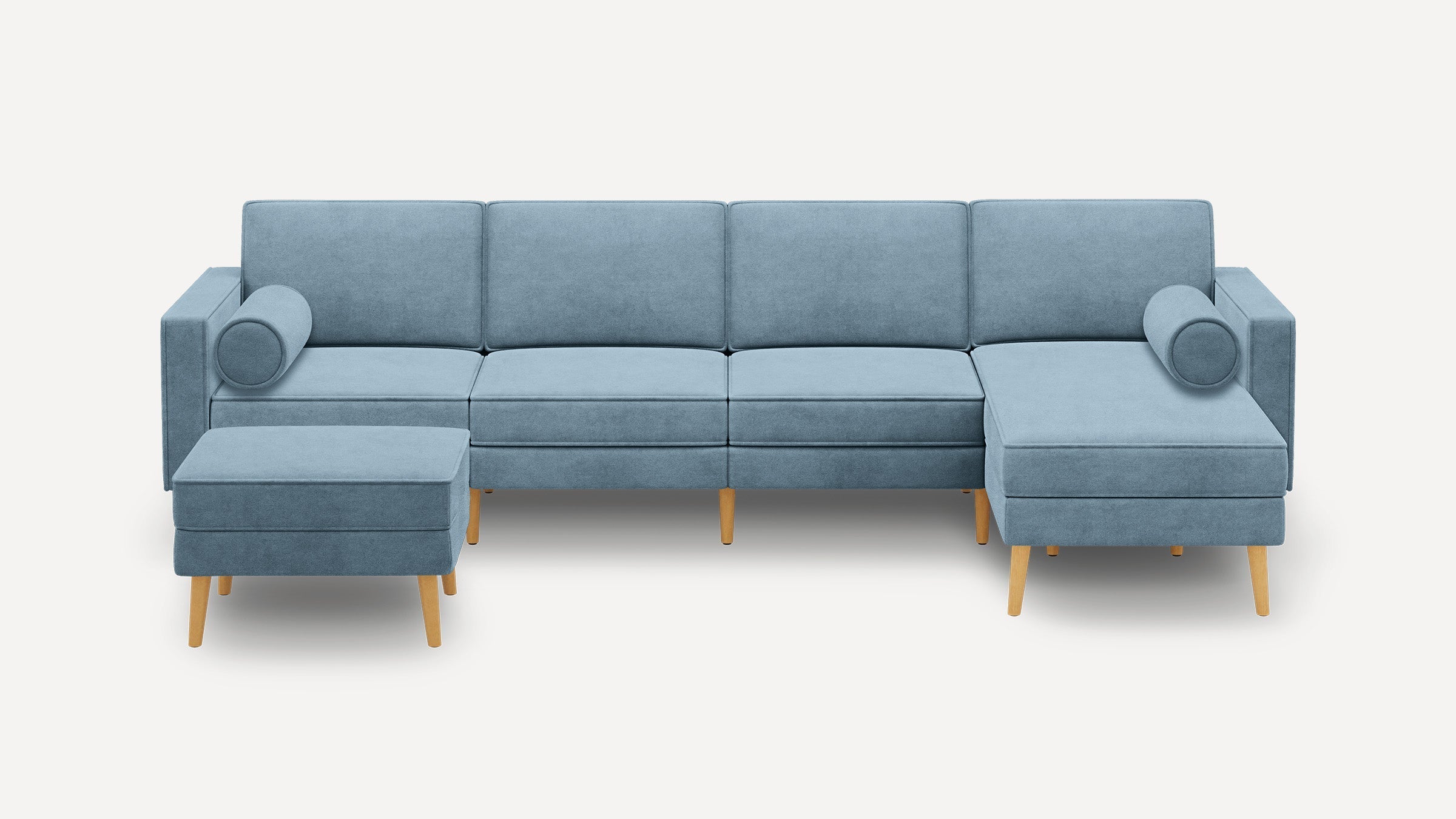 Light blue sectional sofa with wooden legs, includes two cylindrical bolster pillows and a matching ottoman.