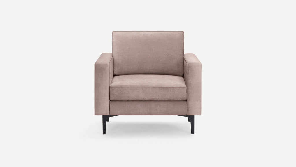Front view of a modern dusty pink armchair with soft cushions and angled black metal legs on a plain white background.