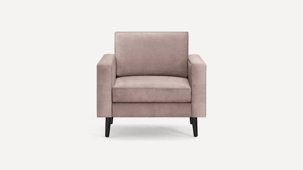 Modern blush pink velvet armchair with square arms and black tapered wooden legs on a plain white background.
