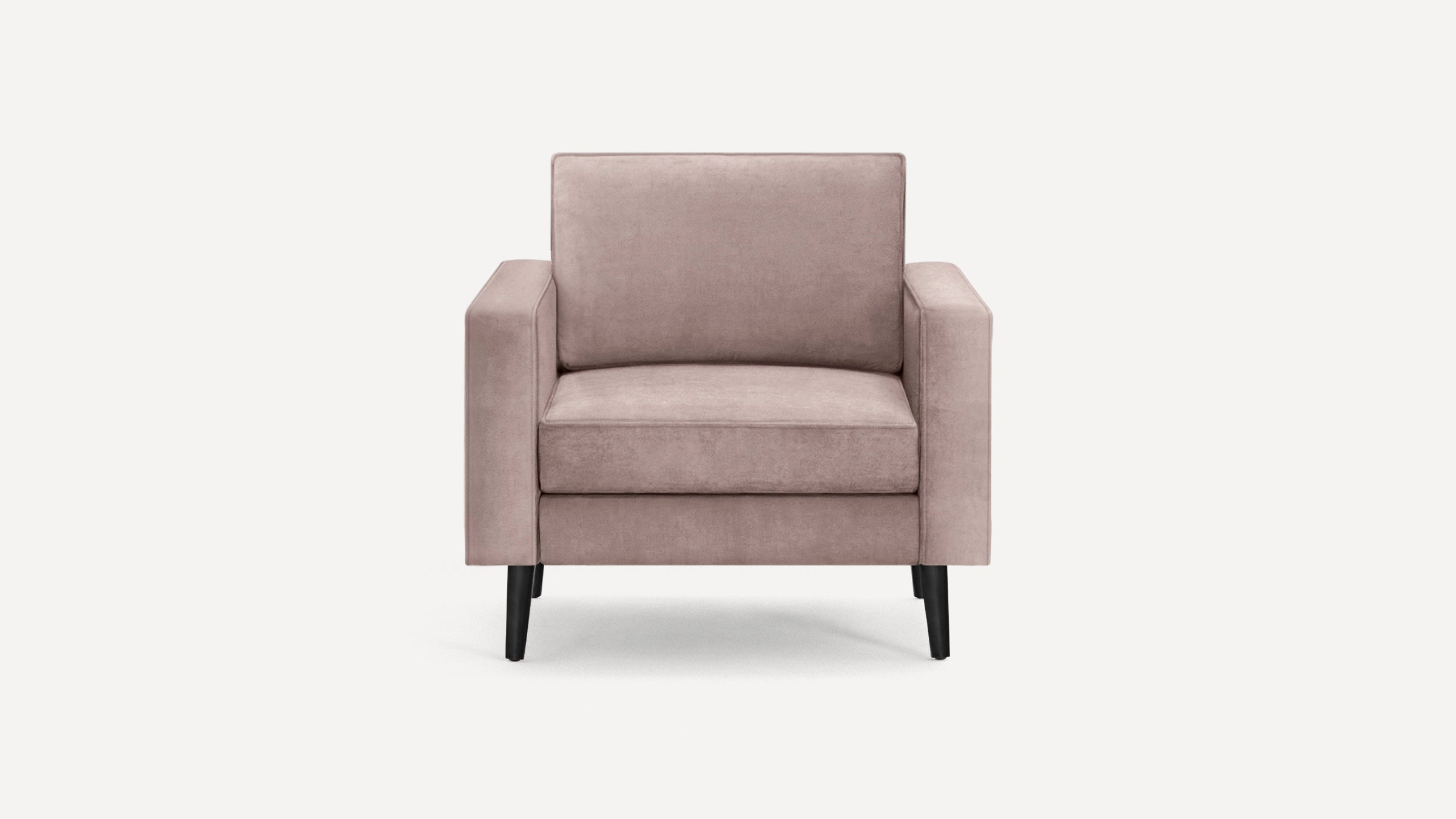 Modern blush pink velvet armchair with square arms and black tapered wooden legs on a plain white background.