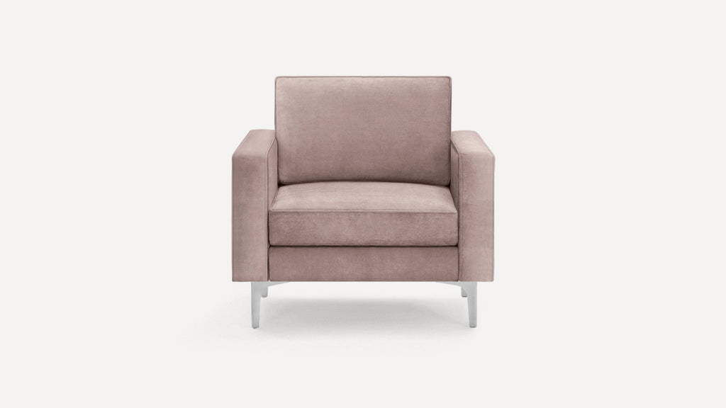 Modern dusty pink velvet armchair with boxy arms and sleek silver metal legs, shown on plain white background.