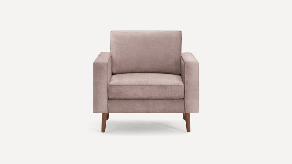 Front view of a modern blush pink upholstered armchair with wooden legs on a plain white background.
