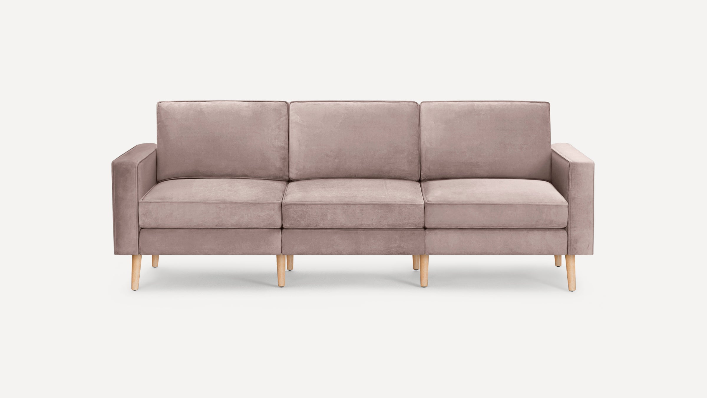 Three-seat modern sofa in muted pink fabric with straight arms and light wooden legs on white background.