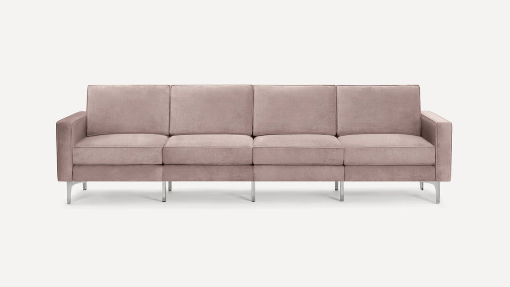 Modern, four-seater sofa with blush pink velvet upholstery and sleek silver metal legs, featuring straight arms and plush cushions.