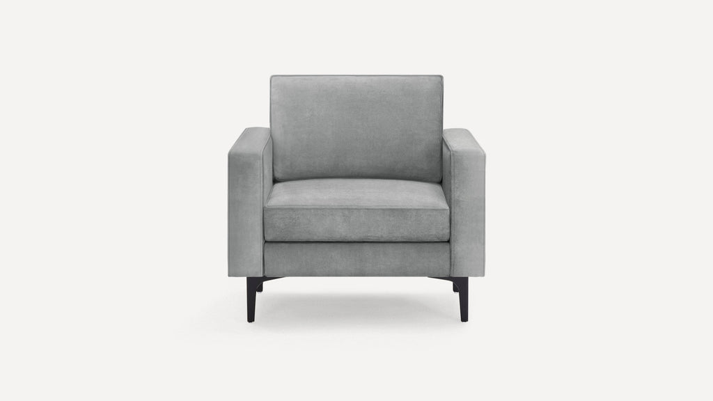 Modern light gray armchair with squared arms and black tapered legs, upholstered in soft fabric.