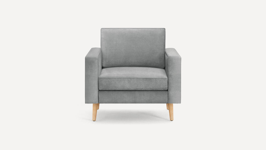 Front view of a modern gray upholstered armchair with wooden tapered legs on a white background.