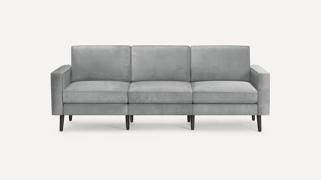 Modern three-seater sofa with light gray upholstery and black tapered legs, featuring clean lines and rectangular cushions.