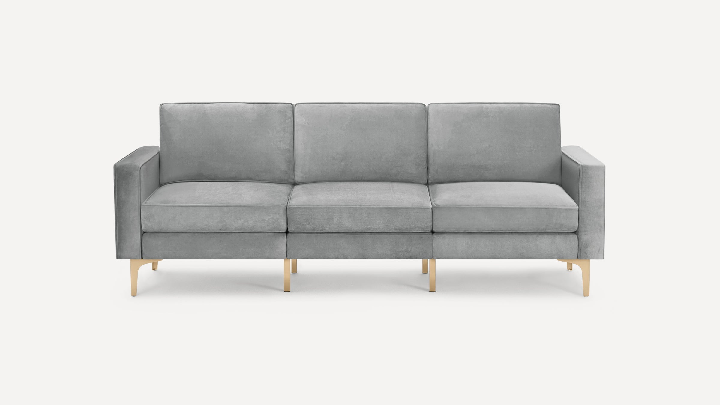 Modern three-seat sofa with light grey velvet upholstery and gold-tone metal legs on a white background.