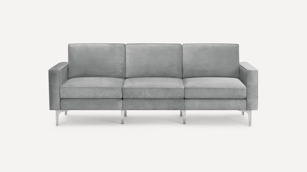 Modern three-seater sofa with soft grey upholstery, clean lines, square armrests, and slim metal legs.