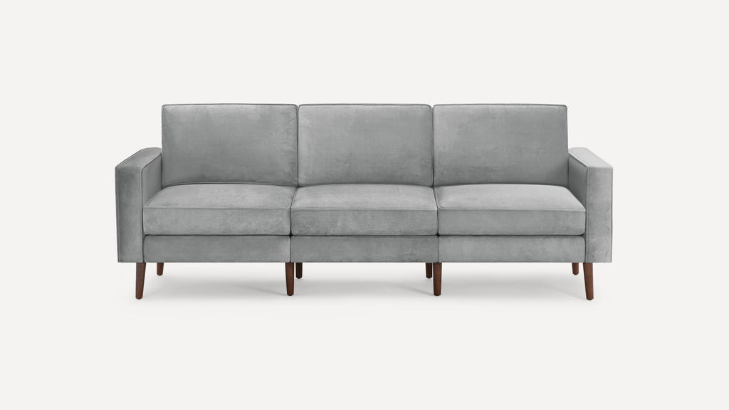 Modern three-seater sofa with light gray fabric upholstery and tapered wooden legs, featuring clean lines and square armrests.