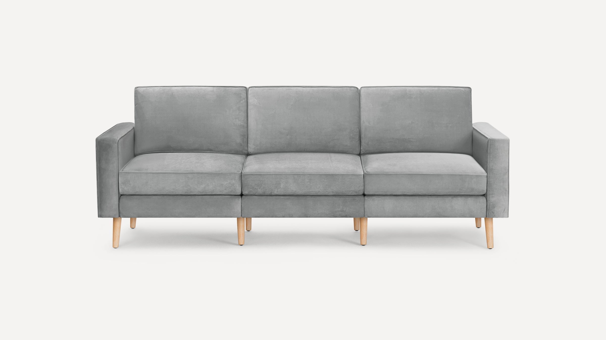 Modern three-seater sofa upholstered in soft gray fabric with straight arms and light wooden legs on a white background.