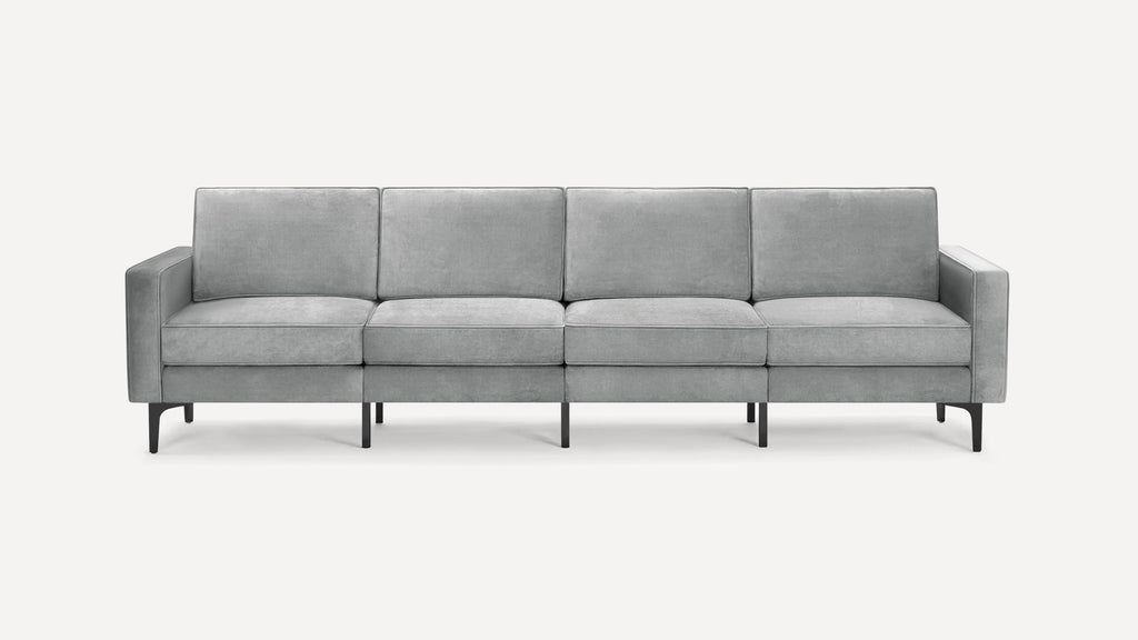 Modern grey velvet four-seater sofa with square arms and black metal legs, shown against a plain white background.