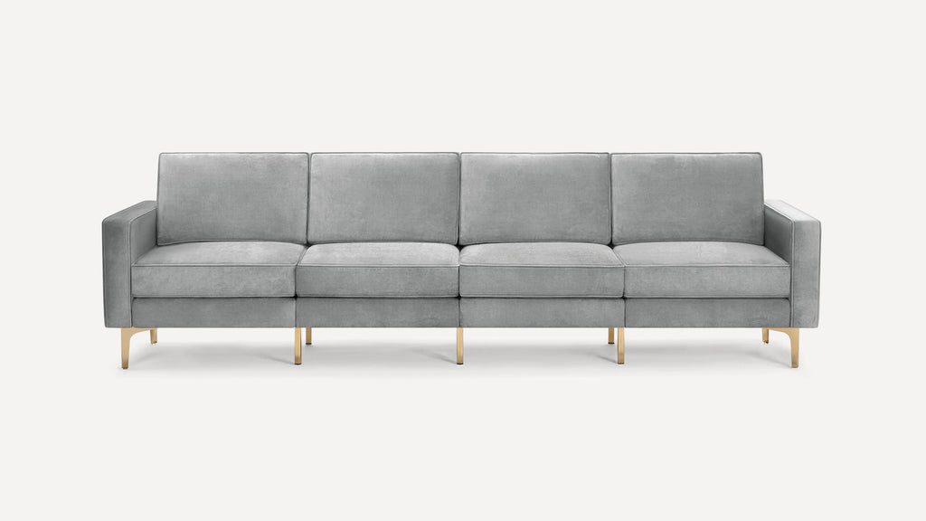 Modern four-seater sofa with light gray velvet upholstery and sleek gold metal legs, featuring clean lines and cushioned armrests.