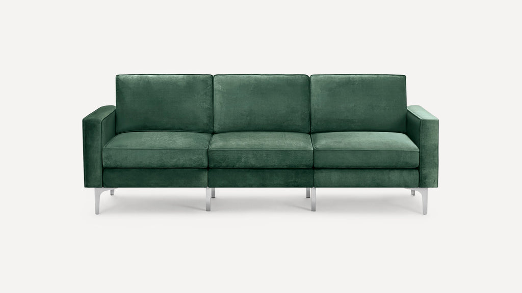 Modern three-seater sofa upholstered in dark green velvet fabric with rectangular cushions and sleek metal legs.