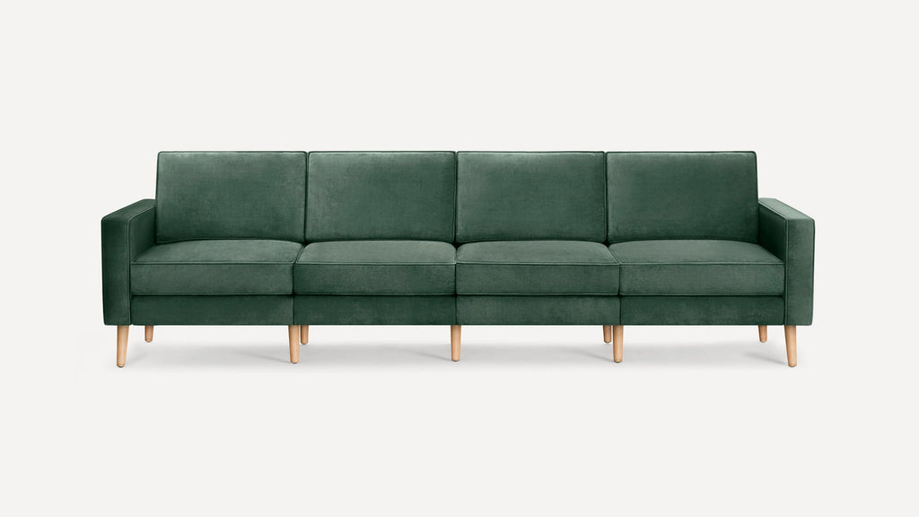 Dark green velvet modern sofa with four seat cushions and light wooden legs, against a plain white background.
