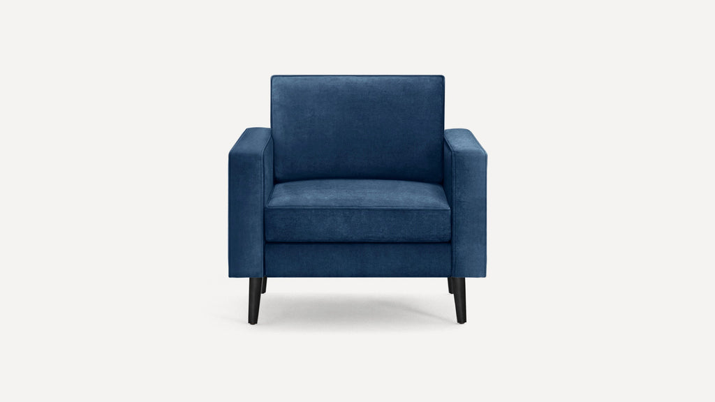 Blue velvet armchair with clean lines, square arms, cushioned back and seat, and dark tapered wooden legs.